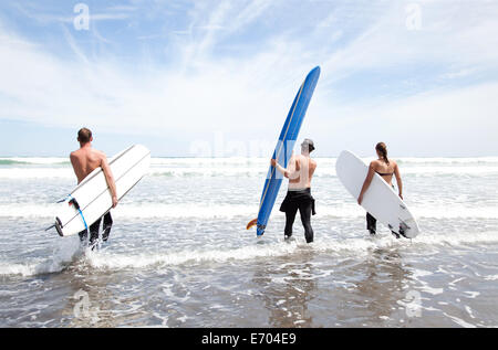 Männliche und weibliche Surfer-Freunde im Meer mit Surfbrettern stehend Stockfoto