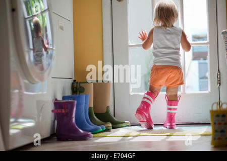 Weiblichen Kleinkind Gummi Stiefel aus Hintertür Fenster Stockfoto