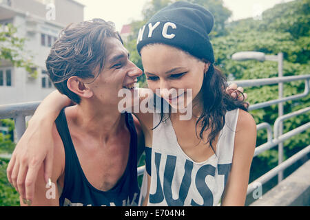 Junges Paar, lächelnd mit Arme umeinander Stockfoto