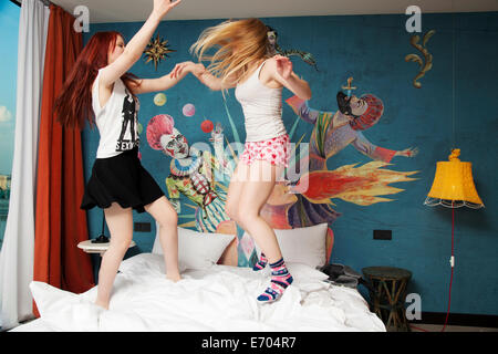 Zwei junge Frauen tanzen auf Hotelbett Stockfoto