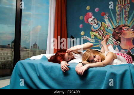 Zwei verschlafene junge Frauen auf Hotelbett liegend Stockfoto