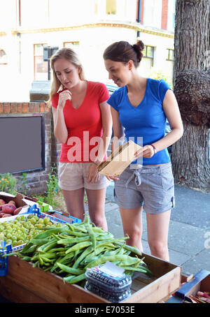 Zwei junge Frauen betrachten am Marktstand Gemüse Stockfoto