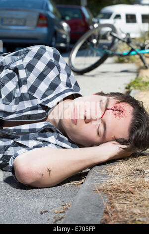 Junger Mann am Straßenrand mit blutende Stirn liegen Stockfoto