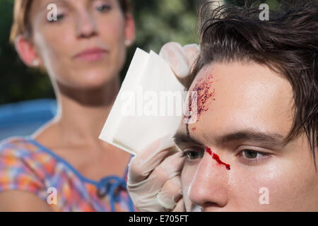 Frau, jungen Mann mit blutende Stirn Reinigung Stockfoto