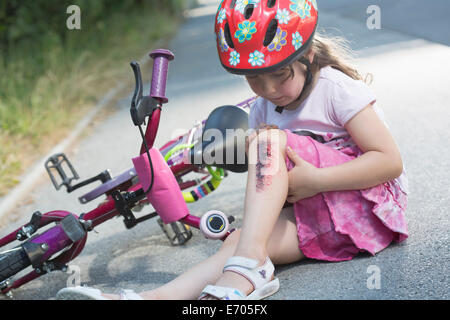 Junges Mädchen mit verletzten Bein sitzen mit dem Fahrrad unterwegs Stockfoto