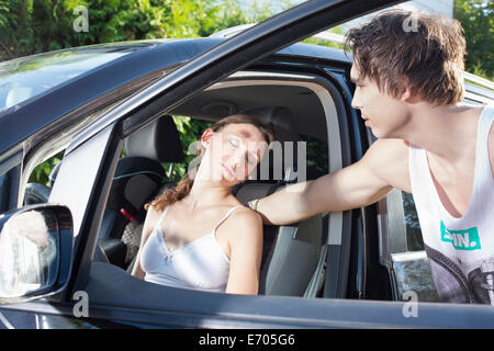 Junger Mann, die Kontrolle über verletzte Fahrerin Stockfoto