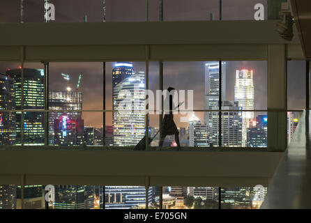 Junge Frau mit Smartphone und ziehen Koffer, Skyline der Stadt im Blick Stockfoto