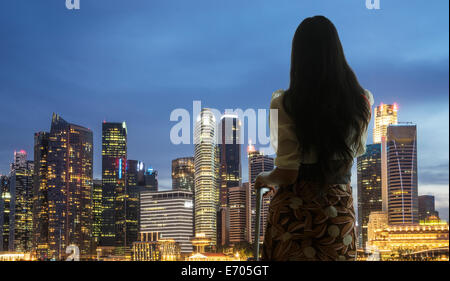 Junge Frau mit Blick auf die Skyline der Stadt Koffer Stockfoto