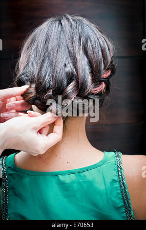 Rückansicht des weiblichen Friseur Flechten junge Frau an den Haaren in Friseursalon Stockfoto