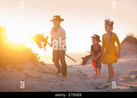 Drei Kinder, verkleidet als Indianer und Cowboys in Sanddünen Stockfoto