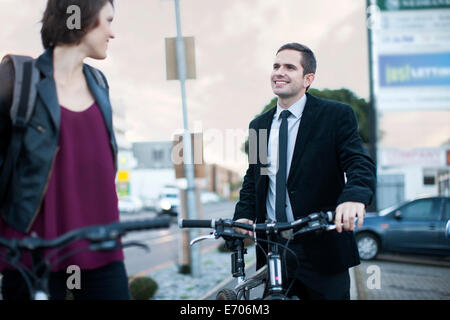 Junge Frau im Gespräch mit Geschäftsmann während Radfahren zu arbeiten Stockfoto
