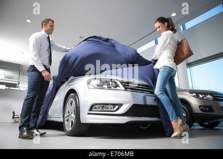 Verkäufer aufdecken Neuwagen an weibliche Kunden im Autohaus Stockfoto