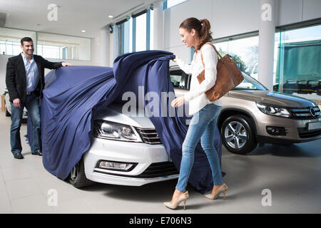 Frau aufdecken Neuwagen mit Freund im Autohaus Stockfoto