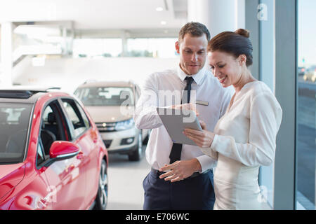 Verkäufer und weibliche Kunden mit digital-Tablette im Autohaus Stockfoto