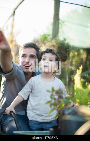 Mitte erwachsener Mann und Sohn suchen überrascht im Garten Stockfoto