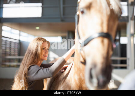 Junge weibliche Stallknecht Palomino Pferd Pflege Stockfoto