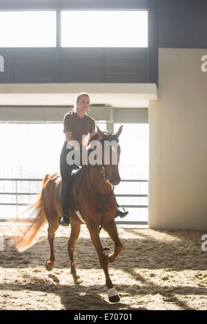 Frau im Trab auf rotes Pferd im indoor-paddock Stockfoto