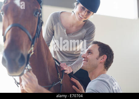 Junge weibliche Reiterin mit Instruktor im indoor-paddock Stockfoto