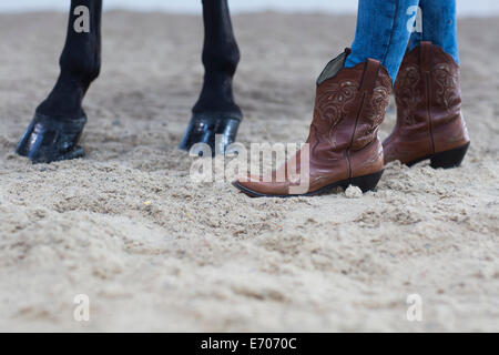 Schuss von Pferdehufen und junge Frau in Cowboystiefeln beschnitten Stockfoto