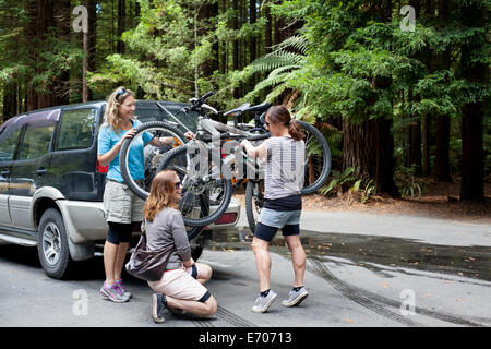 Drei Frauen Mountainbiker Aufhebung Bikes aus vier-Rad-Fahrzeug im Wald Stockfoto