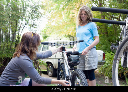 Zwei Frauen Mountainbiker Check-Zyklen in Wald Stockfoto
