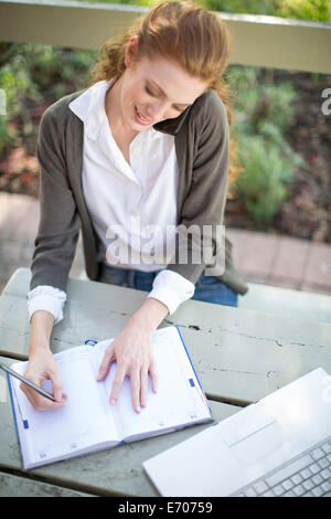 Junge Geschäftsfrau in Arbeit Tagebuch am Gartentisch zu schreiben Stockfoto