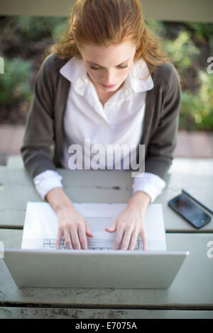 Junge Geschäftsfrau Tippen auf Laptop am Gartentisch Stockfoto