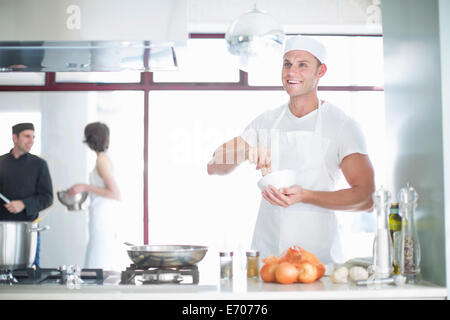 Porträt von lächelnden männlichen Chef mischen mit Mörser und Stößel in Großküchen Stockfoto