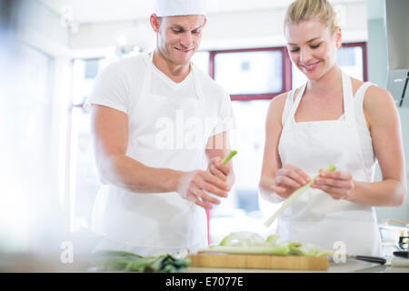 Männliche und weibliche Köche schälen Lauch in Großküchen Stockfoto