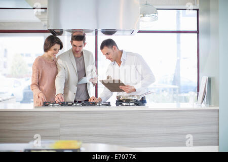 Mitte erwachsenes paar und Verkäufer suchen, am Herd in der Küche showroom Stockfoto