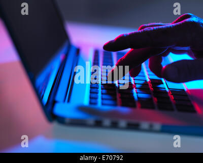 Silhouette der männlichen Hand in der Nacht auf Laptoptastatur tippen Stockfoto