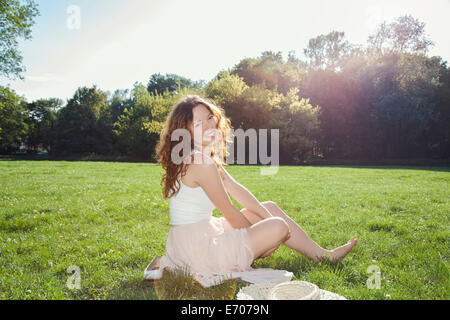 Porträt der jungen Frau sitzen auf Park Rasen Stockfoto