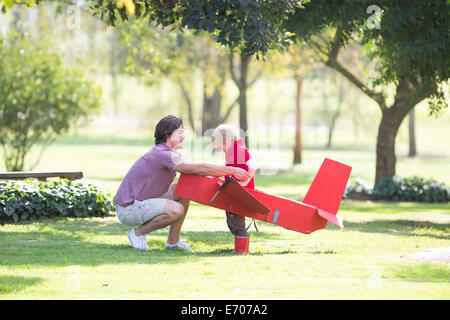 Vater hocken um Spielzeugflugzeug für seinen Sohn im Park vorbereiten Stockfoto