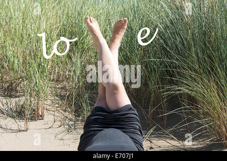 Schwangere Frau mit Liebesbriefe auf dem Bauch im sand Stockfoto