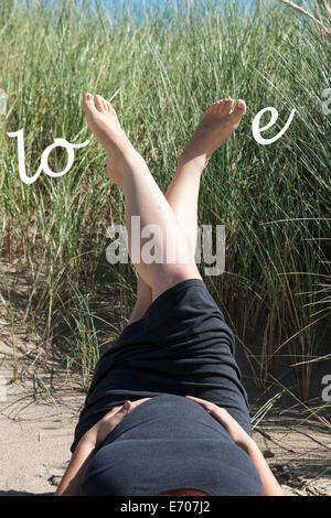 Schwangere Frau mit Liebesbriefe auf dem Bauch im sand Stockfoto