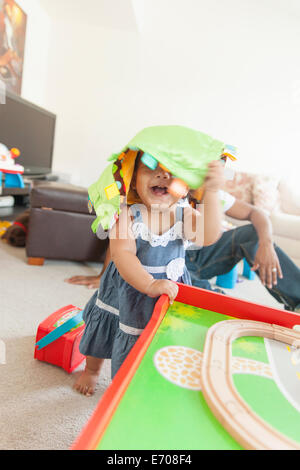 Babymädchen spielen, Vater im Hintergrund Stockfoto