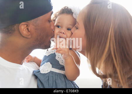 Mutter und Vater junge Tochter auf Wangen küssen Stockfoto