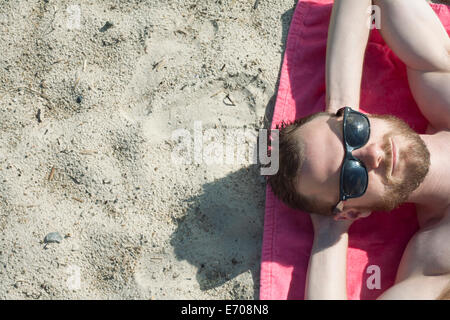 Draufsicht der Mitte erwachsener Mann mit Sonnenbrille auf Sand Sonnenbaden Stockfoto