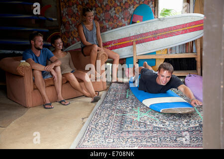 Vier junge Erwachsene Surfer Freunde Herumspielen in Surf Schuppen Stockfoto