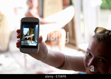 Junge Frau hält Smartphone mit Foto von ihrer besten Freundin Stockfoto