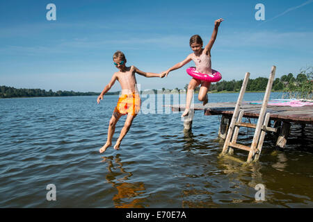 Bruder und Schwester Hand in Hand und in den See springen Stockfoto