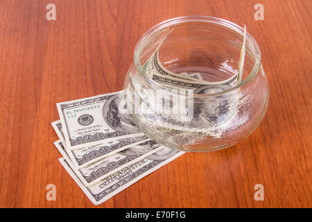 Hundert-Dollar-Banknoten in Glasschüssel auf Holztisch.