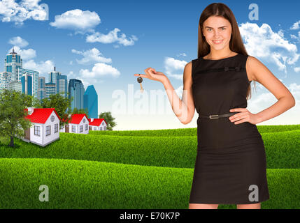 Frau Betrieb Schlüssel. Hochhäuser und Häuser mit Landschaft Stockfoto