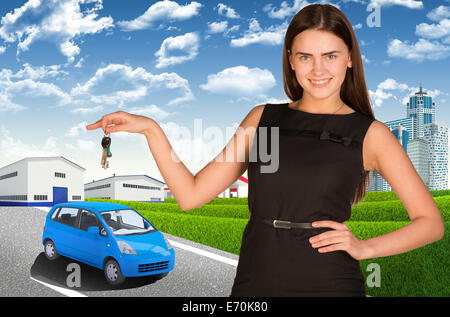 Frau mit Autoschlüssel in der Hand. Kleines Auto unterwegs Stockfoto