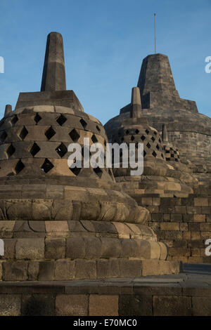 Borobudur, Java, Indonesien.  Drei kleine Stupas, oberste Stupa im Hintergrund.  Symbolische Öffnungen. Stockfoto
