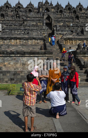 Borobudur, Java, Indonesien.  Indonesische Studenten mit einem Besuch buddhistischer Mönch fotografiert werden. Stockfoto