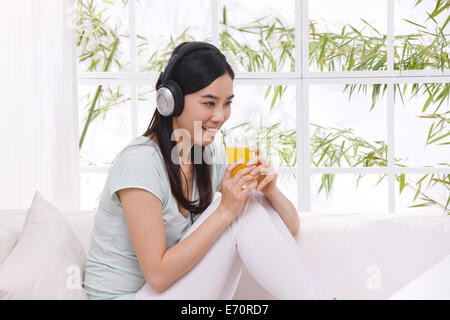 Junge Frau Saft zu trinken und Musik hören Stockfoto
