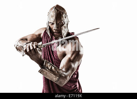 Studioportrait von muskulösen jungen Mann verkleidet als Gladiator mit Helm und Schwert