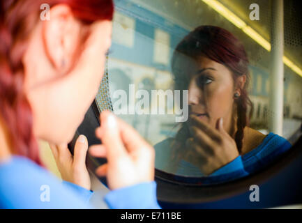 Junge Frau im Waschsalon, Blick auf Reflexion in Waschmaschine Stockfoto