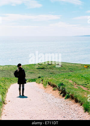 Eine Frau steht auf einer Klippe Weg mit Blick auf das Meer. Stockfoto